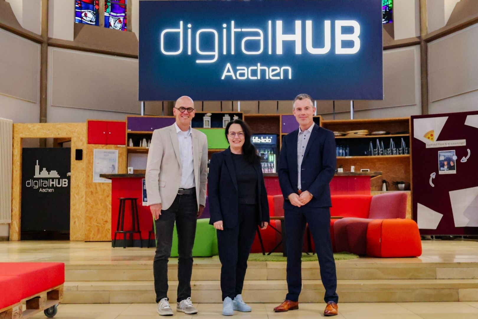 Vertreter der Unternehmen Lancom und Netaachen stehen zusammen mit der Geschäftsführerin des diditalHUB Aachen in der digitalCHURCH vor dem digitalHUB Aachen Logo Vertreter der Unternehmen Lancom und Netaachen stehen zusammen mit der Geschäftsführerin des diditalHUB Aachen in der digitalCHURCH vor dem digitalHUB Aachen Logo