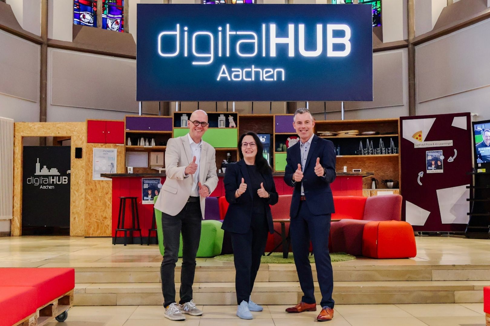 Vertreter der Unternehmen Lancom und Netaachen stehen zusammen mit der Geschäftsführerin des diditalHUB Aachen in der digitalCHURCH vor dem digitalHUB Aachen Logo Vertreter der Unternehmen Lancom und Netaachen stehen zusammen mit der Geschäftsführerin des diditalHUB Aachen in der digitalCHURCH vor dem digitalHUB Aachen Logo